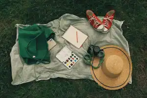 Caneta, celular, bloco de anotações e mochila sobre uma mesa.