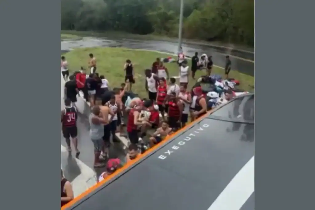 Torcedores do Flamengo observam ônibus tombado na beira da Rodovia Dutra