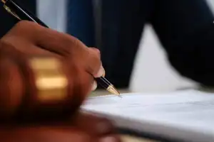 Mão segurando caneta sobre documento, simbolizando decisão judicial e inquérito